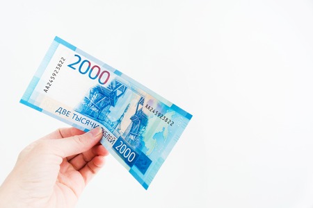 Female hand holds 2000 russian ruble bill on white background with copy space, new russian banknote