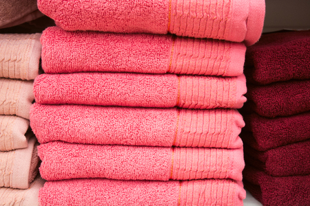 Different pink towels on shelf, soft cozy bathroom texture backgroundの写真素材