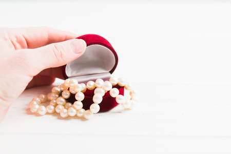 Woman hand is opening jewellery box with pearls necklace with copy space, Valentine's Day or Womans Day gift conceptの写真素材