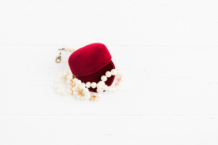 Overhead view of opened red gift jewellry box with necklace of pearls on white wooden background with copy spaceの写真素材