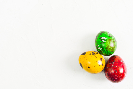 Colorful Easter quail eggs over white textured background with copy space, flat layの写真素材