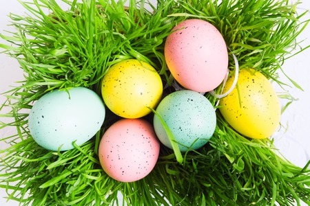 Colorful pastel eggs on green grass, top view. Flat lay style. Decorated Easter eggs