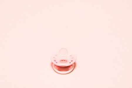 Silicone orthodontic pacifier with ventilation holes for newborn baby over pink background. Children newborn concept. Baby girl plastic relax equipment. Copy spaceの写真素材