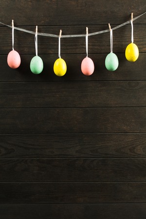Easter pastel decorative eggs with ribbon on rope on wooden background, Easter decortion card with copy space for textの写真素材