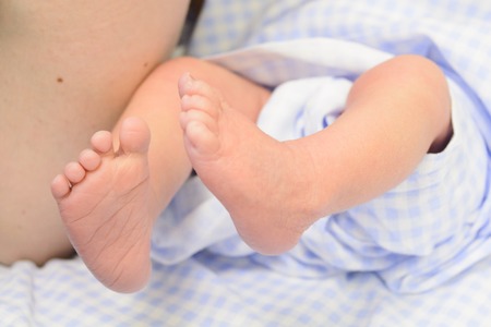 Newborn baby feet in blue nappy. Small cute feet. Selective focusの写真素材