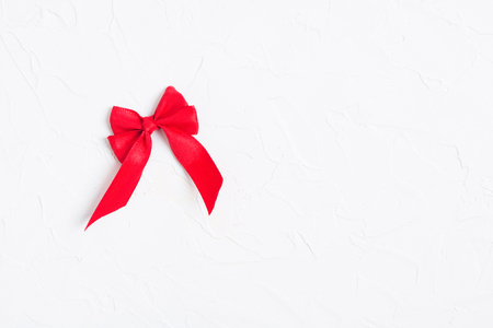 Red bow on white textured background. Copy space. Mock up. Flat lay. Top viewの写真素材