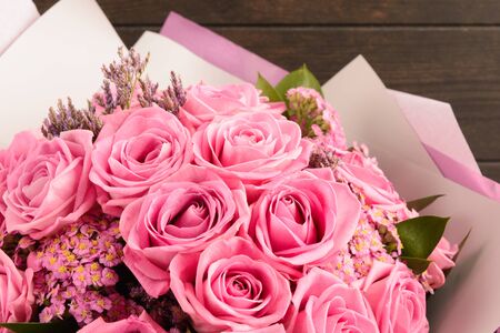 Beautiful bouquet of pink roses for Valentine's day in pink and grey paper with wooden background, selective focus, Closeup viewの写真素材