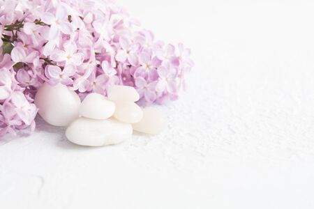 White stones with lilac over white textured background. Spa concept, aromatherapy. Selective focusの写真素材
