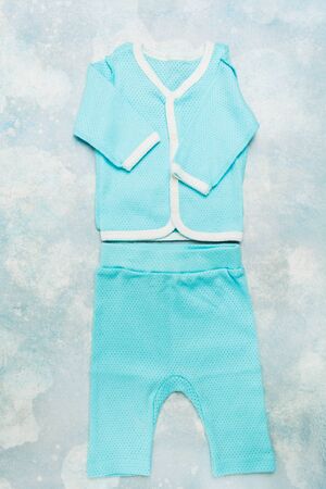 Fashionable cotton textile summer suit for newborn baby on blue textured background. Flat lay style. Vertical shotの写真素材