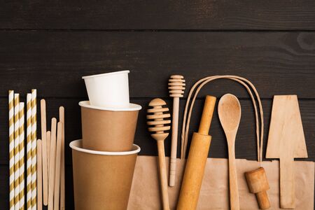 Zero waste concept with wooden utensile and paper cups and bag on wooden background with copy space. Flat layの写真素材