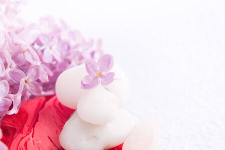 Spa and massage relaxation concept with white stones. red handmade soap and lilac flowers on white textured background with copy space. Selective focusの写真素材