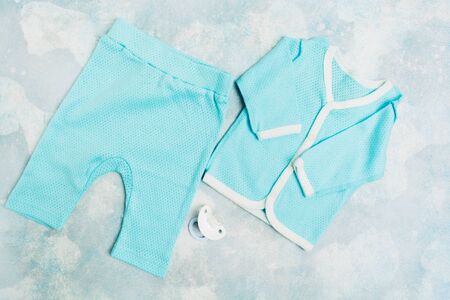 Blue baby suit of cotton with white silicone pacifier. Flat lay style. Top view. Baby fashionの写真素材
