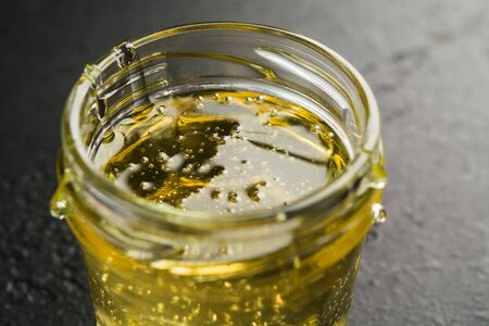 Glass jar with light sweet flower honey on dark background. Closeup view. Macro. Selective focusの写真素材