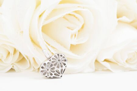 Beautiful golden heart shape jewelry with white roses on background with copy space. Valentine's day gift. Symbol of love. Selective focus. Mockupの写真素材