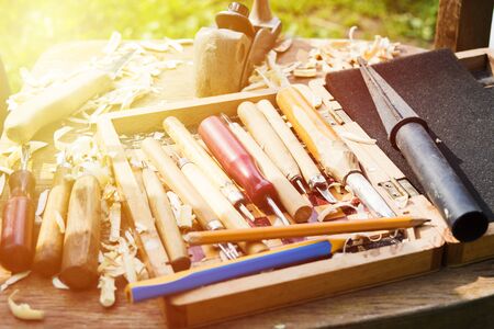 Different tools for wood carving in wooden box with wood shavings. Selective focus with sunlight....