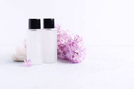 Two plastic bottle with shower gel or shampoo for bath with lilac aroma and natural flowers. Spa concept. Copy space. Selective focusの写真素材