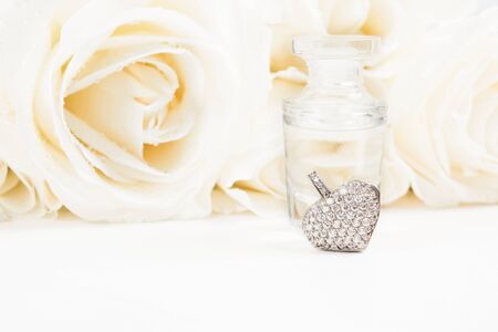 Valentine's day gift with bouquet of white roses, fragrance and heart pendant with diamonds. Copy space. Soft focus. Wedding presentの写真素材