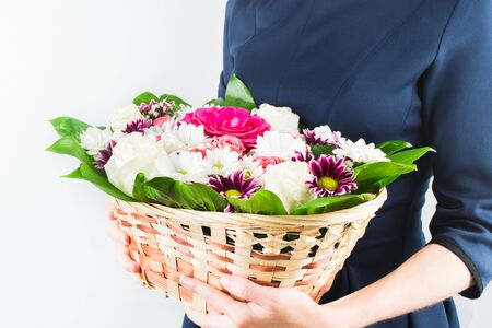 Woman in blue dress holding flowers in wicker basket in hands. White background. Copy spaceの写真素材