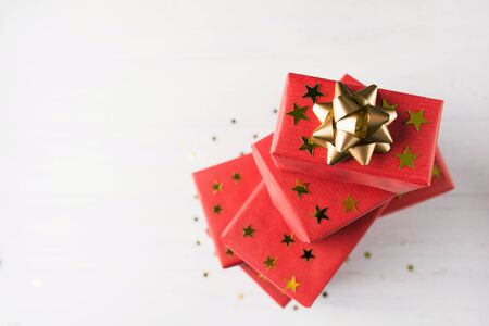 Stack of presents in red paper with golden stars decoration and golden bow on top. Copy spaceの写真素材