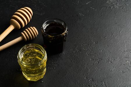 Light and dark honey. Healthy vegetarian natural food against flu for warming. Dark photo on black stone background. Copy spaceの写真素材
