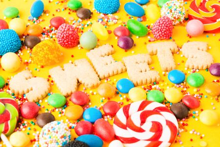 Colorful unhealthy sweet candies. Mix for holiday. Sweet table for Birthday on yellow background. Selective focusの写真素材