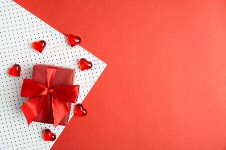 Red gift box with bow on wrapping paper with hearts. Valentine's day's cocncept. Copy space. Flat lay. Top viewの写真素材