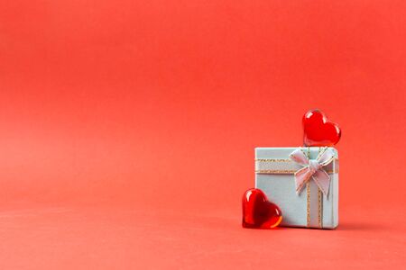 Valentine's day present with bow and red hearts. Love concept with holiday gift on red background. Copy space. Soft focusの写真素材