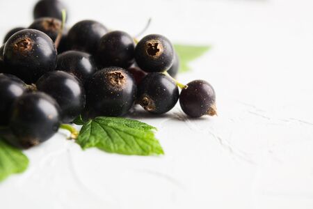 Stack of healthy fresh black currants with green leaves over white textured background. Copy space. Vegetarian foodの写真素材