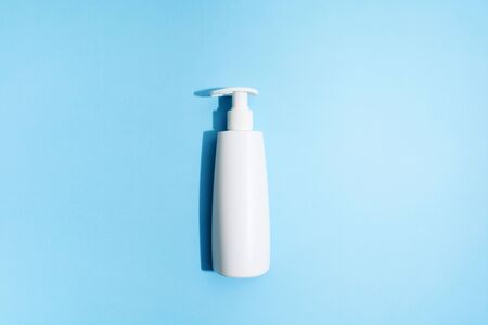 White plastic bottle on blue background. Mockup. Flat lay. Sanitizer gel for prevention of virus. Covid-19. Hard light. Blue background. Shower gel or liqiud soap. Hygiene concept. Top viewの写真素材