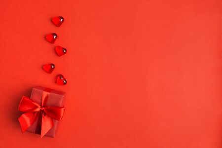 Red gift box with red bow with red hearts over red background with copy space. Flat lay. Velntine's day, Woman's day or Wedding's present concept. Beautiful elegant present. Holiday design backdropの写真素材