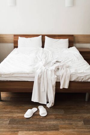 Bathrobe over bed in hotel room with slippers. Vertical shotの写真素材