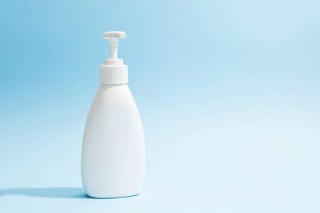 White plastic bottle with dispenser. Sanitizer, liquid soap, shampoo or shower gel mockup on blue background. Copy spaceの写真素材