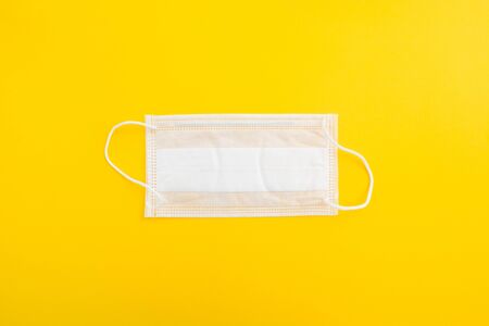 Medical mask on yellow background. Flat lay. Top view. Protection against virusの写真素材
