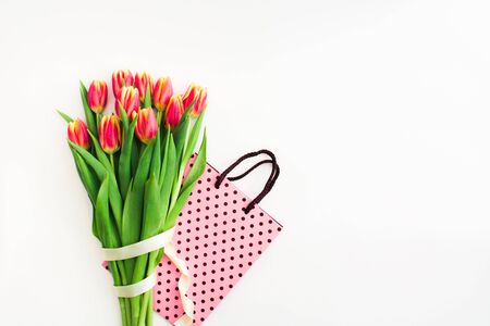 Beautiful spring bouquet of pink tulips flowers with white ribbon with bag on white. Flat lay. Copy space. Womans day or Valentines day gift. Concept of holiday spring sale in store or online shoppingの写真素材