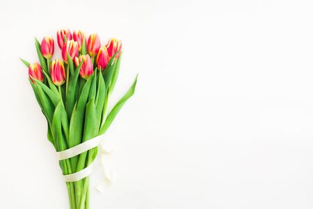 Beautiful spring bouquet of pink tulips flowers with white ribbon on white background. Flat lay. Copy space. Womans day, Valentines day and Mothers day conceptの写真素材