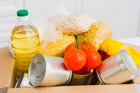 Closeup view of box with many different products for donation. Coronavirus donation box concept. Selective focus. Canned food, preservedの写真素材