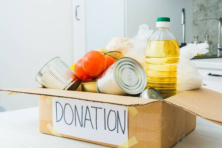 Donation food in cardboard box in kitchen. Help for people in quarantine time. Charity concept.の写真素材