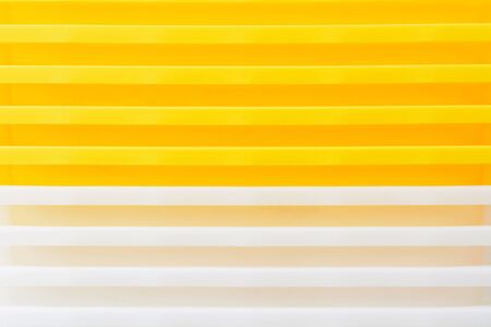 Stack of yellow and white recycled plastic containers. Duocolor background. Closeup view of...