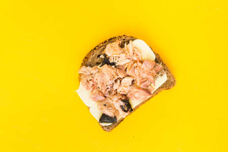 Red fish preserve on wholegrain bread over yellow backgroundの写真素材