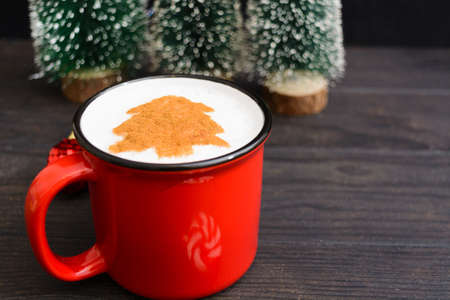 Christmas cup of coffee with fir tree pattern. New Year beverage on wooden tableの写真素材