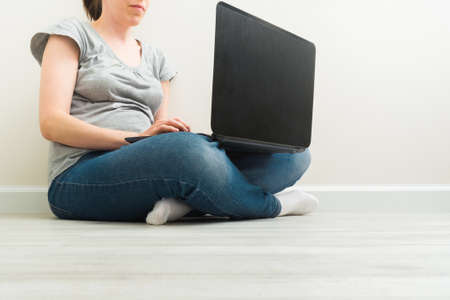 Croped caucasian woman sitting on floor and working with a laptopの写真素材