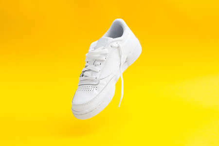 Womens stylish white casual sneakers on yellow background. Copy spaceの写真素材