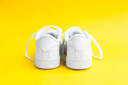 Womens stylish white casual sneakers on yellow backgroundの写真素材