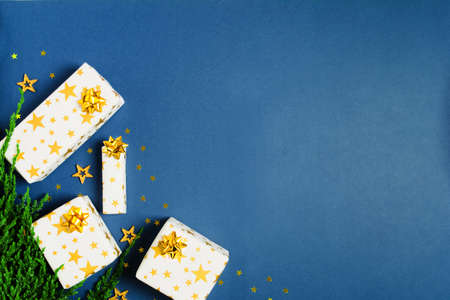 Holiday gift with wrapping paper with stars and golden bows with confettiの写真素材