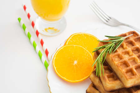 Breakfast with belgium waffles with rosemary and orange slices. Closeup viewの写真素材