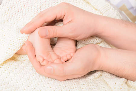 Baby feet in male hands with soft background, close-up. Selective focusの写真素材
