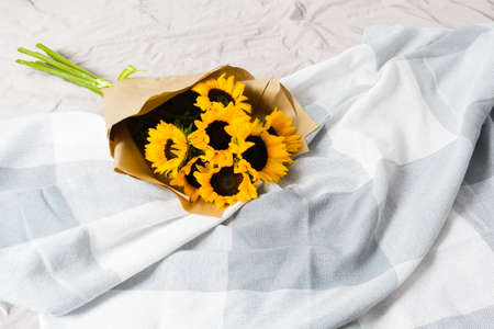 Beautiful authentic yellow sunflowers bouquet with craft paper in bed