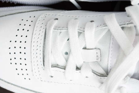 Pair of female stylish white casual sneakers on yellow backgroundの写真素材