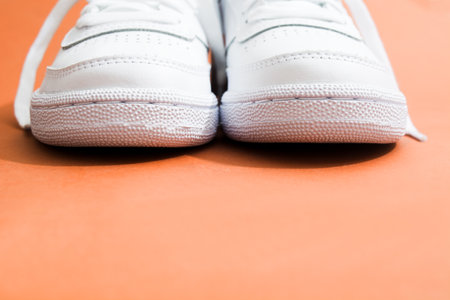 Front view of pair of female stylish white casual sneakers on brown backgroundの写真素材