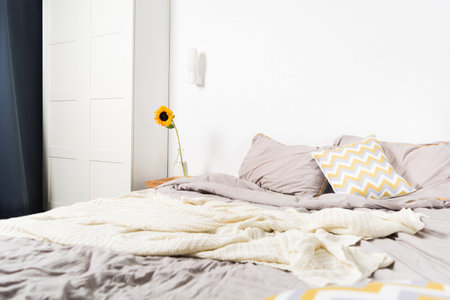 Single beautiful yellow sunflower in vase near bed in bedroomの写真素材